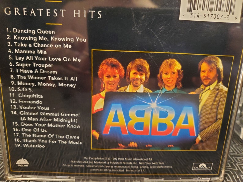 May include: ABBA's Greatest Hits CD. The album cover features the band members and the ABBA logo in blue and yellow. The tracklist includes popular songs like "Dancing Queen" and "Mamma Mia".