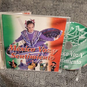 May include: CD case featuring the album "México Voz y Sentimiento." The cover art showcases a woman in a traditional Mexican dress, with the album title in red and white. A separate CD is visible.