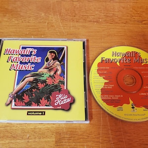 May include: A CD case and disc for "Hawaii's Favorite Music, Volume 1." The case features a woman playing a ukulele, surrounded by flowers. The disc is yellow and red with song titles.