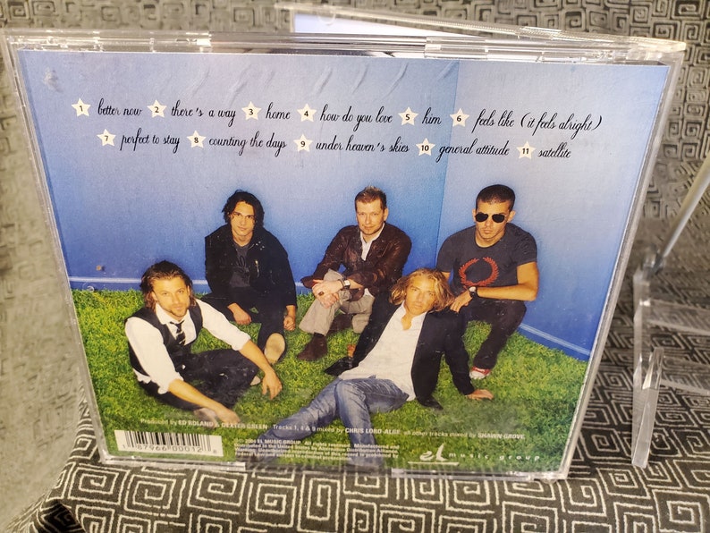 May include: A CD case with a blue background and a group of five men posing on a green lawn. The back of the case lists the track titles and song names: "better now", "there's a way", "home", "how do you love", "him", "feels like (it feels alright)", "perfect to stay", "counting the days", "under heaven's skies", "general attitude", "satellite".