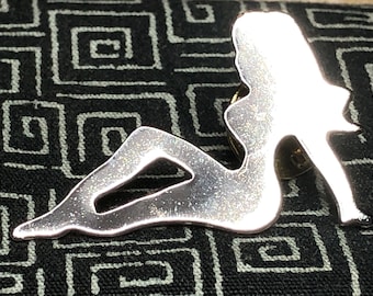 Épinglette cache-boue argentée Chevy - Pays hors-la-loi - Silhouette nue - Femme - Nu - Chevrolet - Chevrolet - La femme est tournée vers la droite lorsqu'elle est épinglée dessus