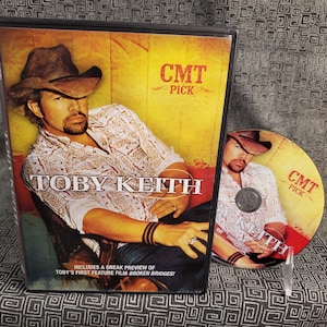 May include: A DVD case featuring Toby Keith with a yellow background and the text "CMT Pick". The case includes a sneak preview of Toby Keith's first feature film "Broken Bridges".