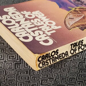 May include: A paperback book titled "Tales of Power" by Carlos Castaneda. The cover features a butterfly with a brown and white pattern against a sunset background.