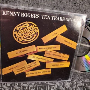 May include: A CD case with a gold background and a picture of Kenny Rogers. The title of the album is "Kenny Rogers Ten Years of Gold". The CD case has a list of songs on the back.