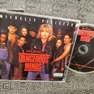 May include: A CD case with a black background and the text "Dangerous Minds" in red. The case features a group of people, including Michelle Pfeiffer, on the front. The CD is also visible, with a black background and the text "Dangerous Minds" in red.
