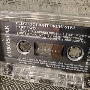 May include: A black cassette tape with a clear plastic case. The tape is labeled "Electric Light Orchestra Part Two" and includes the song titles "Hello", "Honest Men", "Every Night", "Once Upon A Time", and "Heartbreaker". The tape is a stereo recording and was made in Germany.