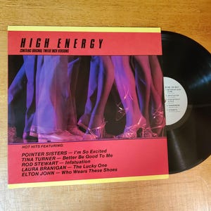 May include: A vinyl record album titled "High Energy" with a red and yellow cover. The cover features a blurred image of legs and high heels. The album includes songs by Pointer Sisters, Tina Turner, Rod Stewart, Laura Branigan, and Elton John.