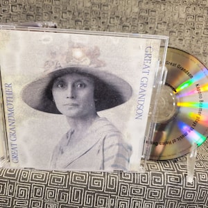 May include: A CD case featuring a sepia-toned portrait of a woman in a wide-brimmed hat. The text "GREAT GRANDMOTHER" and "GREAT GRANDSON" are visible. The CD is visible next to the case, with the text "Kapono Beamer plays the music of Helen Desa".