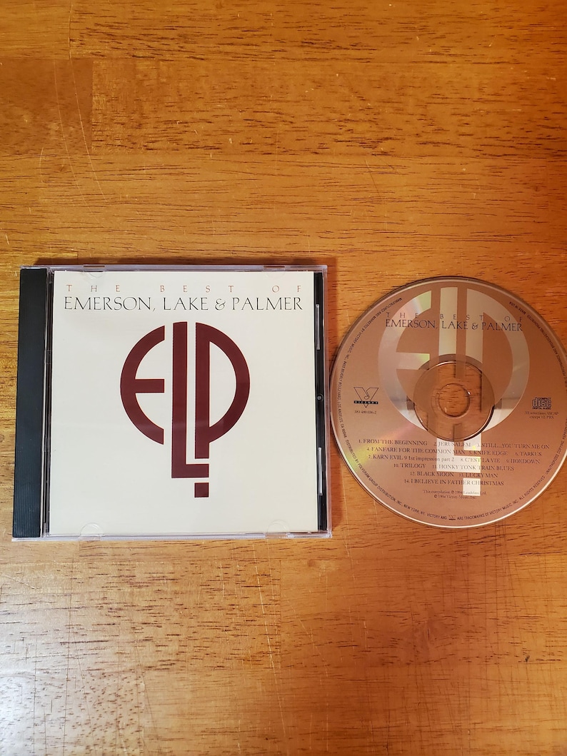 May include: A CD case and disc featuring "The Best of Emerson, Lake & Palmer." The CD case is white with a black spine and the letters "ELP" in a maroon color. The CD is brown with the band's name and song titles.