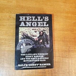 May include: A hardcover book titled Hell's Angel: The Life and Times of Sonny Barger and the Hell's Angels Motorcycle Club by Ralph "Sonny" Barger with Keith and Kent Zimmerman. The black cover features a photograph of a person on a motorcycle.