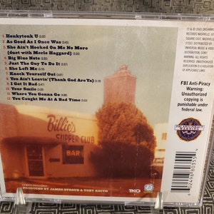 Może przedstawiać: Pudełko na płytę CD ze zdjęciem budynku z napisem "Billie's Chipper Club". Na tylnej stronie pudełka wymieniono tytuły utwor&oacute;w "Honkytonk U" i "As Good As I Once Was", a także umieszczono ostrzeżenie przed nielegalnym kopiowaniem.