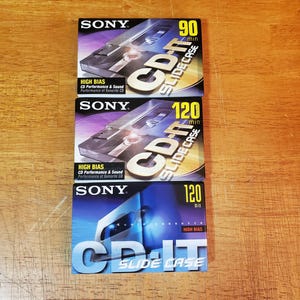 May include: Three Sony CD-IT Slide Case audio cassette tapes. The top tape is labeled 90 min, the middle tape is 120 min, and the bottom tape is also 120 min. All tapes have a blue and silver design.