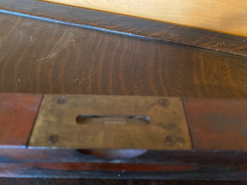 May include: A vintage wooden level with a brass level indicator. The level is made of dark wood and has a brass strip with a level indicator in the center.