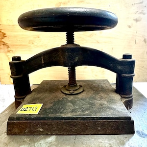 May include: A vintage cast iron book press with a large hand crank. The press is in good condition with some rust and wear. The number 02713 is visible on the base.