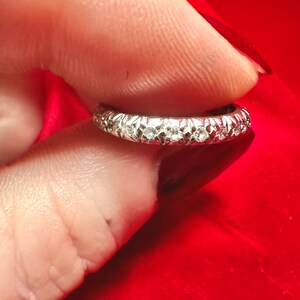 The sides of the solid platinum band are accented with hand engraving, in a vintage Art Deco style.