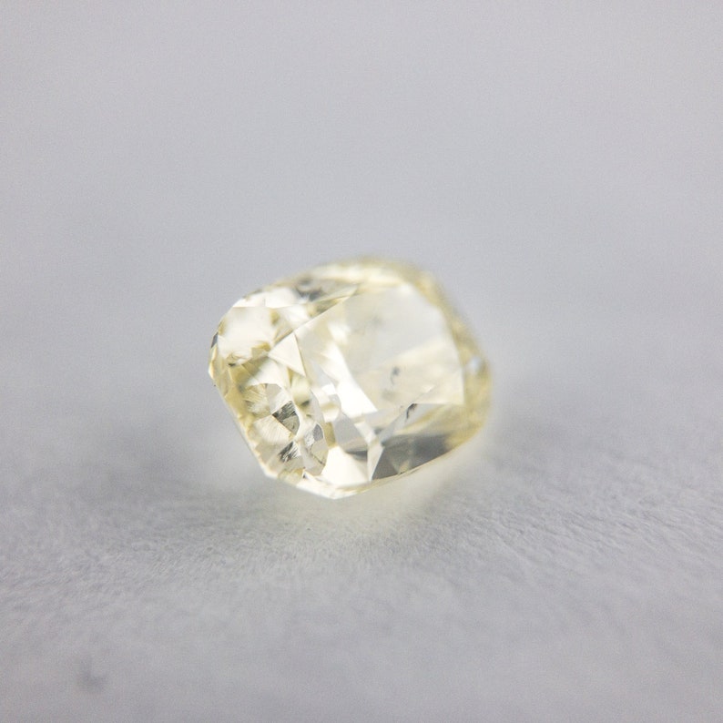 May include: A pale yellow gemstone with a rectangular shape and many facets.