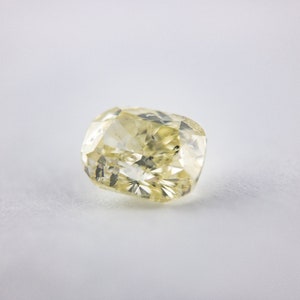 May include: A pale yellow cushion-cut diamond gemstone.
