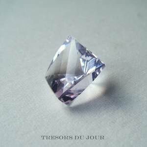 May include: A clear, faceted, light purple gemstone with a square shape.