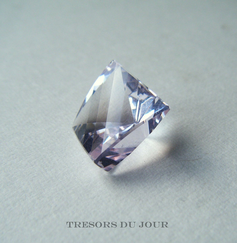 May include: A clear, faceted, light purple gemstone with a square shape.