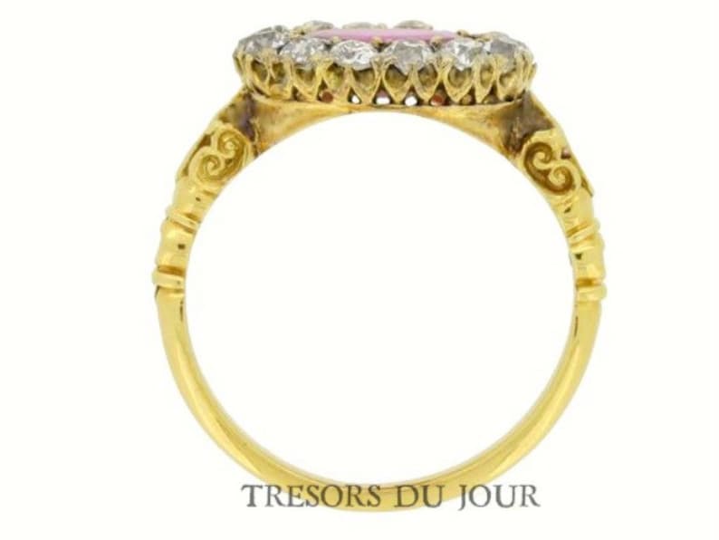 Peut inclure: Bague en or avec une pierre rose entour&eacute;e d'un halo de diamants. Le corps de la bague est en or uni, avec des d&eacute;tails d&eacute;coratifs pr&egrave;s du sertissage. La bague est sur fond blanc. Le texte "TRESORS DU JOUR" est visible.