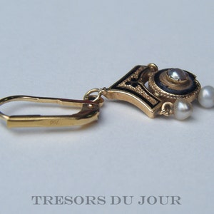 May include: Gold earring with a black enamel and pearl design. The earring has a hook closure and three pearls.