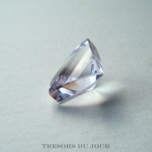 May include: A faceted amethyst gemstone with a light purple hue. The gemstone is cut into a unique shape with many facets.