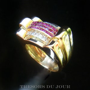 Puede incluir: Un anillo de oro con una banda de diamantes y una fila de rubíes. El anillo está engastado en un diseño único con una banda elevada.