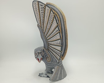 May include: A detailed owl sculpture with outstretched wings. The owl is primarily gray with intricate patterns in black, white, and gold. The beak is red. The wings are spread wide, showcasing the detailed design. The sculpture is on a white background.