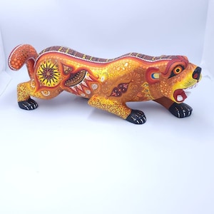 May include: A hand-carved wooden jaguar figurine with intricate details and vibrant orange, yellow, and black paint.