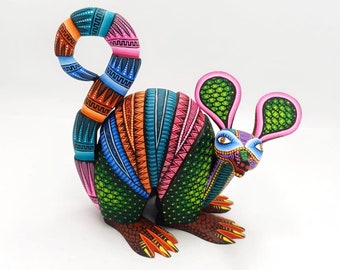 May include: A colorful, hand-painted wooden armadillo figurine with a curled tail and large ears. The armadillo is painted in shades of green, blue, orange, pink, and purple with intricate geometric patterns.