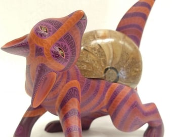 May include: A hand-carved wooden fox figurine with a shell on its back. The fox is painted in shades of orange, pink, and purple with intricate geometric patterns.
