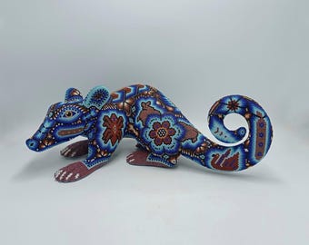 May include: A blue and brown beaded animal figurine of a opossum. The figurine is detailed with intricate floral patterns and is posed in a crouching position.
