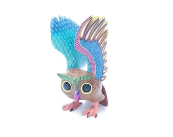 May include: A hand-carved wooden owl with intricate details. The owl is brown with blue and green wings and yellow accents. The owl's eyes are large and black with yellow pupils.