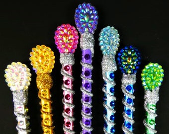 Puede incluir: Siete lápices coloridos con tapas brillantes y enjoyadas. Los lápices están envueltos en purpurina plateada y tienen un diseño en espiral. Las tapas enjoyadas son en tonos de morado, rosa, azul, verde y amarillo.