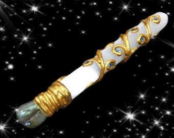 May include: A white selenite wand with gold accents and blue crystals. The wand is set against a black background with white stars.