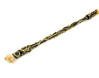 May include: A gold-toned metal wand with intricate details and a clear quartz crystal at the end.