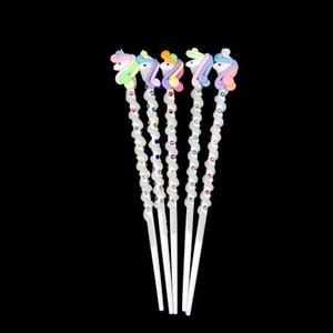 May include: Five white unicorn-shaped hair sticks with rainbow colored manes and tails. Each stick is decorated with colorful rhinestones.
