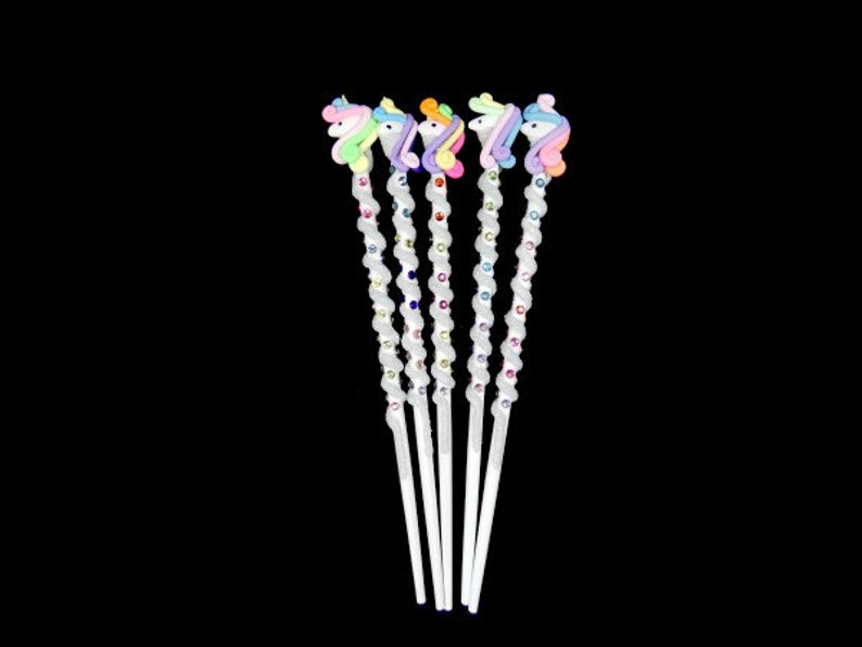 May include: Five white unicorn-shaped hair sticks with rainbow colored manes and tails. Each stick is decorated with colorful rhinestones.
