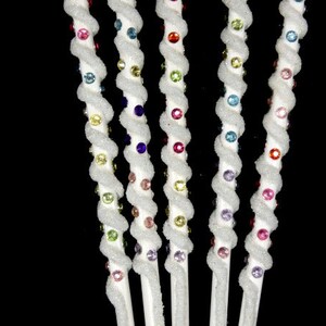 May include: Five white, twisted, decorative sticks with colorful beads. The beads are arranged in a rainbow pattern.
