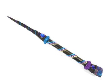 May include: A black wand with a spiral design and blue and purple glitter accents. The wand is decorated with blue and purple gems.