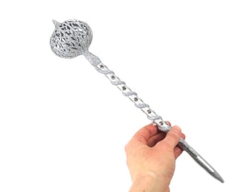 May include: A silver glitter Christmas tree topper with a swirling design and a large, ornate bulb at the top.