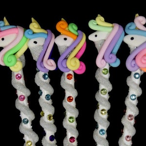 May include: Five unicorn-shaped pencils with rainbow colored manes and tails. The pencils are white with a spiral of glitter and colorful rhinestones.
