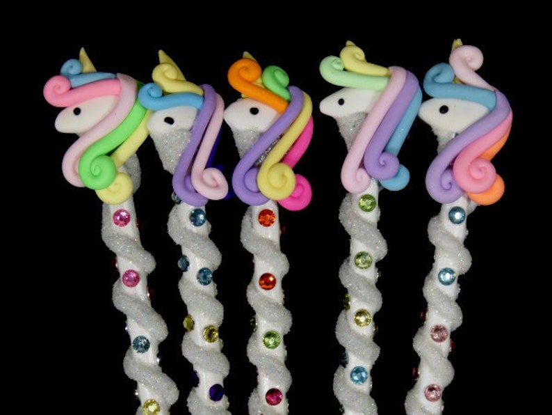May include: Five unicorn-shaped pencils with rainbow colored manes and tails. The pencils are white with a spiral of glitter and colorful rhinestones.