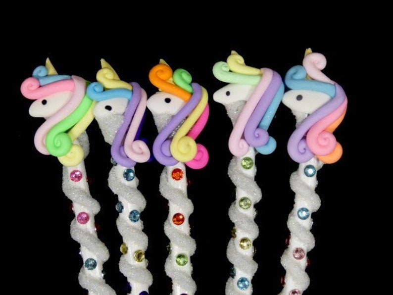May include: Five unicorn-shaped pens with sparkly white bodies and colorful manes. The manes are pink, purple, orange, light blue, and green.