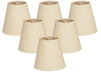 May include: Set of six off-white fabric lampshades in a simple, conical shape.