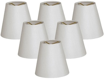 May include: Set of six white fabric lampshades with a simple, conical shape. The lampshades are designed for use with small light bulbs.