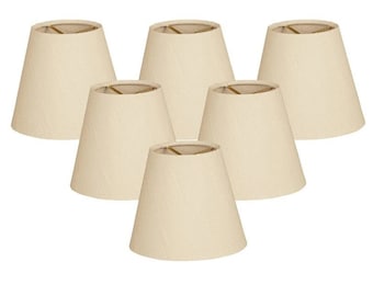 May include: Set of six off-white lampshades with a simple, classic design. The shades are made of fabric and have a slightly flared shape.