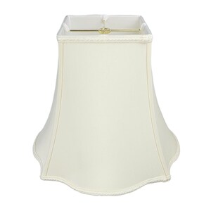 May include: A white, off-white, or cream-colored lampshade with a scalloped bottom edge. The lampshade is made of fabric and has a simple, elegant design.