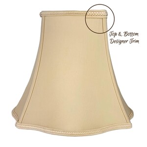 May include: A beige lampshade with a scalloped bottom edge and a decorative trim around the top and bottom. "Top & Bottom Designer Trim" is written in brown text on the image.