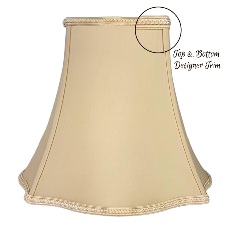 May include: A beige lampshade with a scalloped bottom edge and a decorative trim around the top and bottom. "Top & Bottom Designer Trim" is written in brown text on the image.